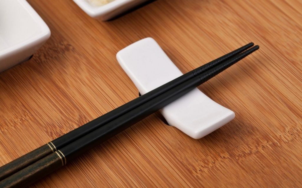 Chopsticks resting on a porcelain rest.